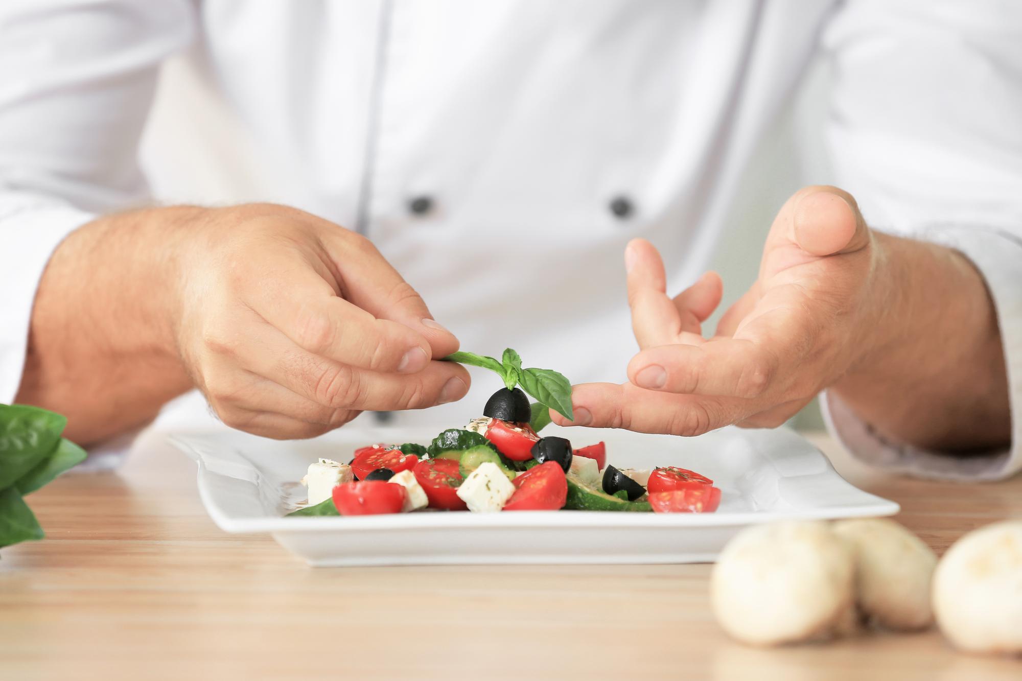 Chef preparing a composed local dish on wooden table